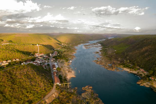 A breathtaking aerial view showcasing Piranhas City and the serene São Francisco River surrounded by lush hills.