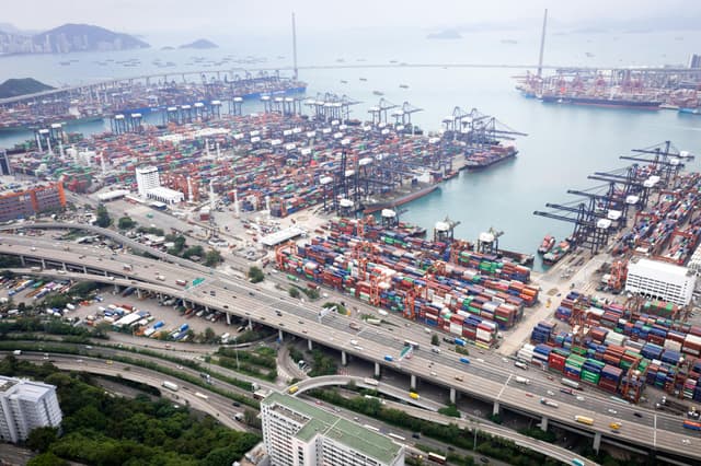 Aerial photo of bustling Kwai Tsing Container Terminal in Hong Kong, showcasing vibrant activity and urban infrastructure.