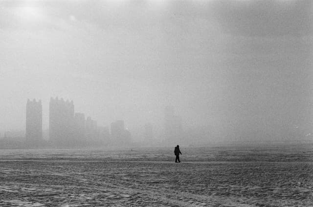 A mysterious figure walks in a foggy Harbin cityscape, creating an eerie atmosphere.