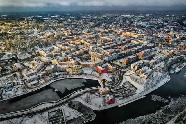 A stunning aerial view of Uppsala covered in snow, showing urban architecture and waterways.