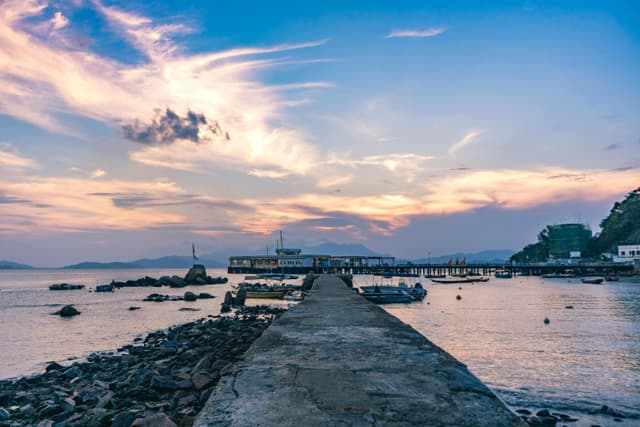 Tranquil sunset view of Sai Kung Pier in Hong Kong with boats and colorful sky.