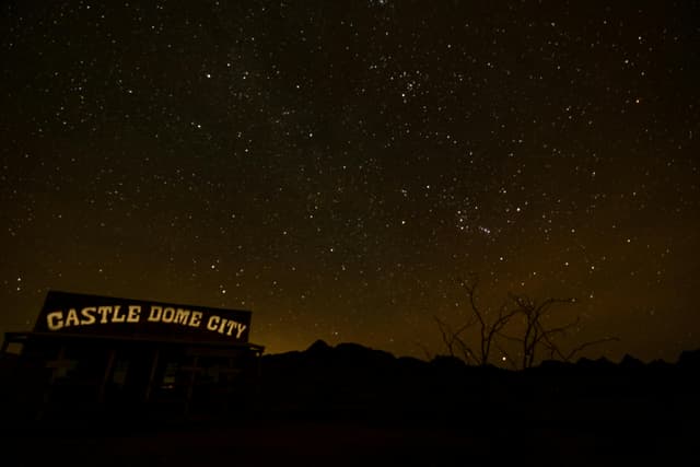 Silhouette of Castle Dome City under a vibrant, starry night sky in Yuma, Arizona.