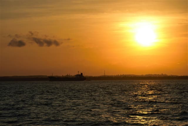 A tranquil sunset casts a golden glow over the sea in Balikpapan, Indonesia.