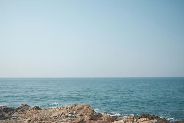 Serene view of the ocean meeting rocky coastline at Phe Beach, Thailand.