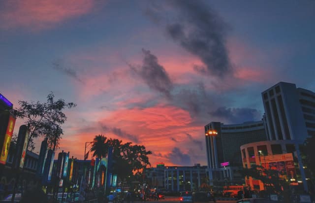 Vivid sunset over Thiruvananthapuram cityscape with buildings silhouetted against colorful sky.