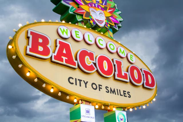 Vibrant Bacolod city sign, known as the City of Smiles, under dramatic sky.