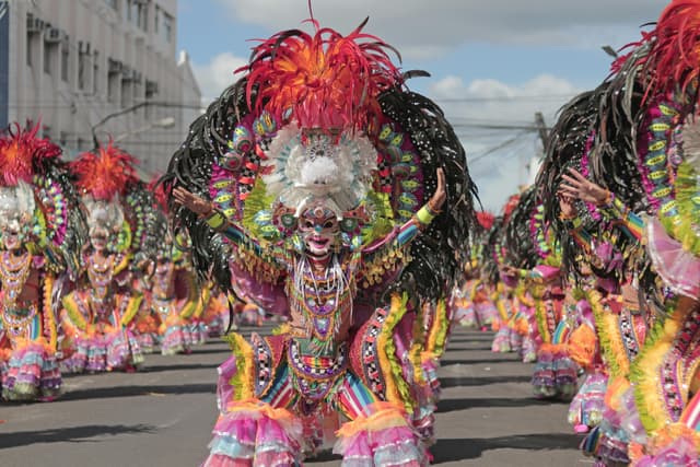 A lively street parade showcasing colorful costumes and masks in a festive atmosphere.