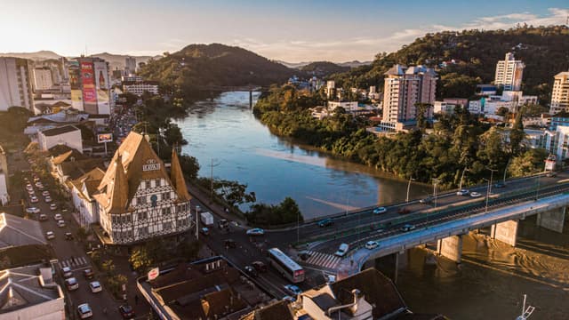 A stunning aerial view of Blumenau, Brazil highlighting the city's architecture and river at sunset.