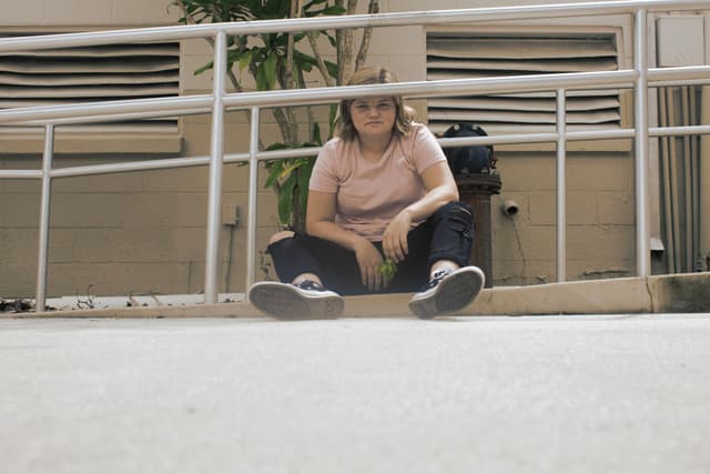 Casual young woman sitting outdoors in urban environment on a sunny day.