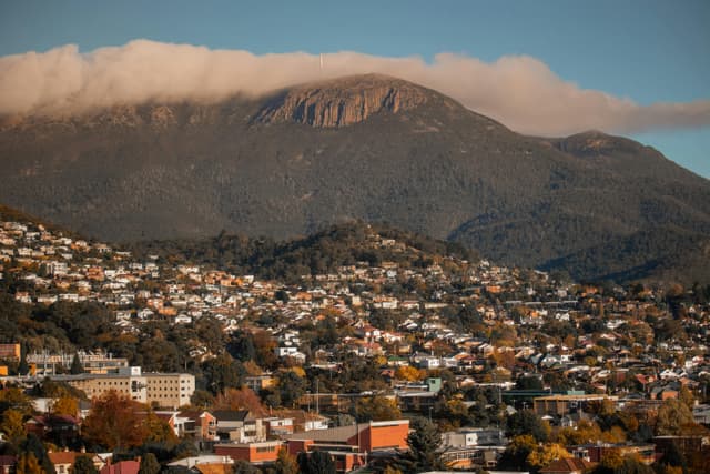Scenic aerial shot of Hobart, Tasmania, featuring Mount Wellington looming in the background.