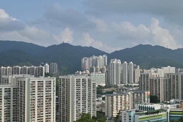 A wide view of Hong Kong's urban landscape featuring skyscrapers against a mountain backdrop.