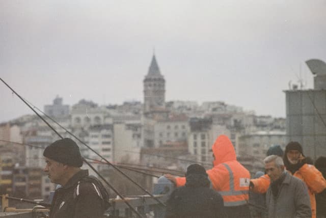 Fishermen near Galata Tower in Istanbul, Turkey, create a vibrant cityscape in a classic urban setting.