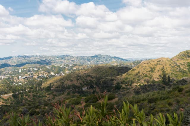Breathtaking panorama of Los Angeles hills with skyline under a cloudy blue sky.