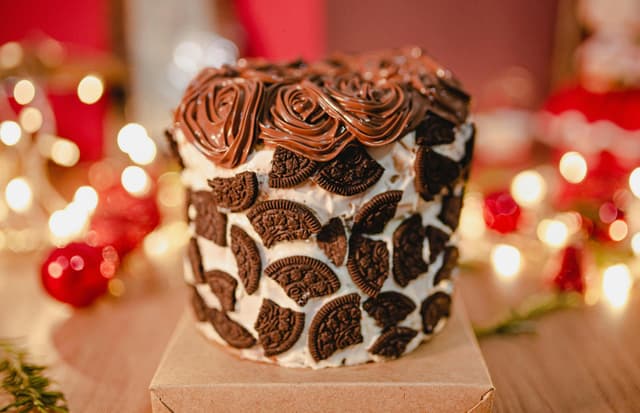 Delicious chocolate cake topped with cookies and intricate frosting, perfect for celebrations.