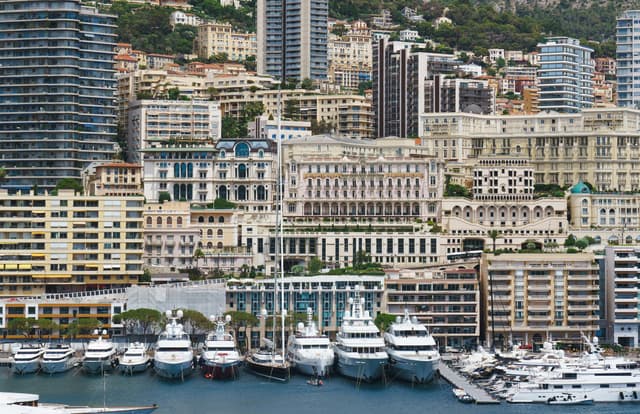 Luxurious yachts moored along Monaco's stunning marina with city skyline.