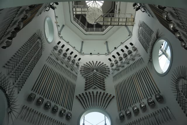 A collection of medieval weapons on display in a historic armory room with ornate design.