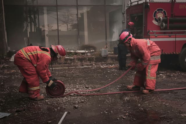 Firefighters manage hoses during a city street operation in Makassar, Indonesia.