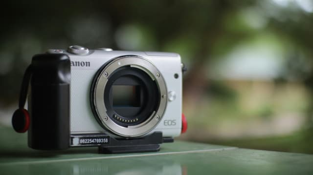 Detailed view of a mirrorless camera outdoors with blurred background.