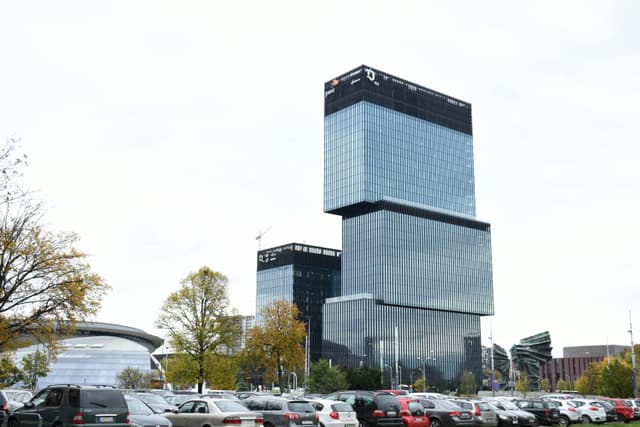 Modern architecture of an office building in Katowice, Poland, with cars and trees in the foreground.