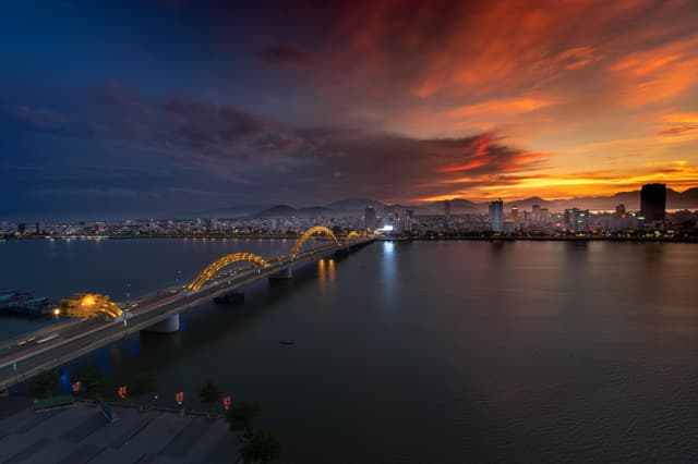 Beautiful sunset over the illuminated Dragon Bridge in Da Nang, Vietnam, highlighting the vibrant cityscape.