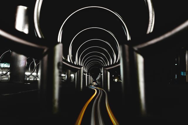 Abstract view of an urban tunnel at night with dynamic light trails and an industrial design.