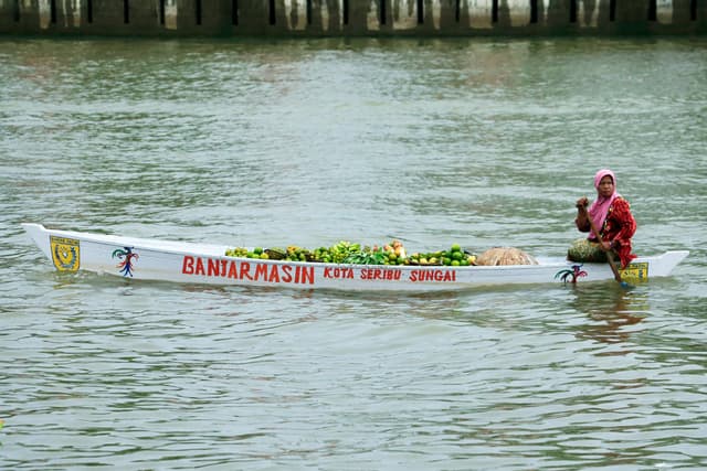 A woman sells fresh produce from a traditional boat in Banjarmasin, Indonesia.