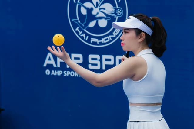 Side view of a female athlete in white gear tossing a ball at a sports event in Hai Phong.