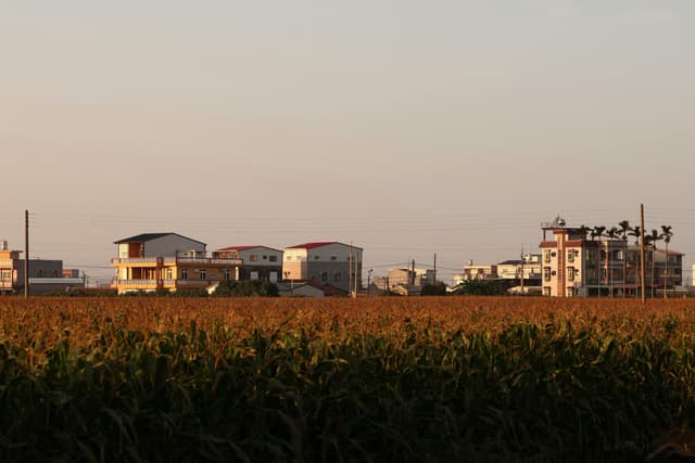 Scenic view of rural Chiayi City, Taiwan, with sunset colors illuminating farmlands and buildings.