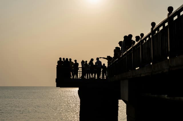 A serene view of people silhouetted against the sun on a pier in Colombo.