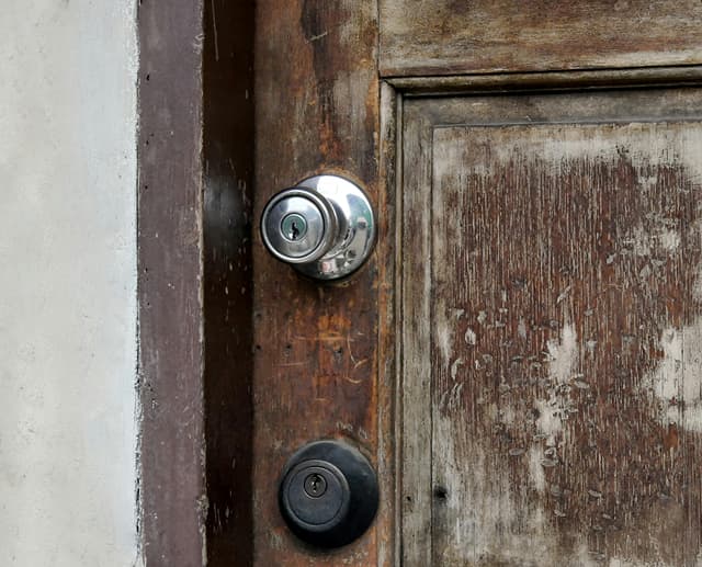 Close-up of a weathered wooden door with metal locks, showcasing aged and rustic features.