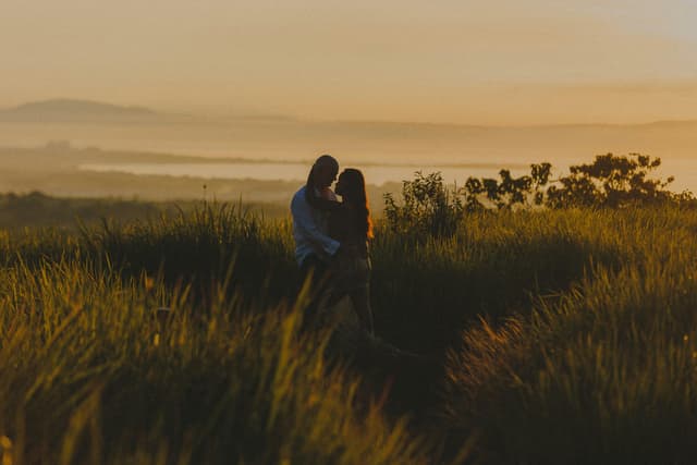 A couple shares a tender moment in a grassy field during sunset in Davao, Philippines.