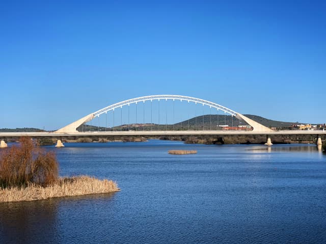 Stunning view of the Lusitania Bridge spanning the Guadiana River under a clear blue sky.