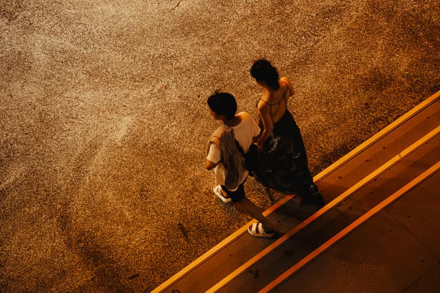 Aerial view of a couple walking together at night on a warm lit sidewalk in Ningbo, China.