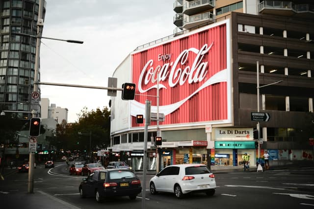 Sydney's famous Coca-Cola billboard lights up a busy street corner.