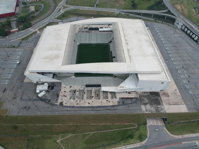 High-angle shot of a contemporary stadium from above, surrounded by parking and roads.
