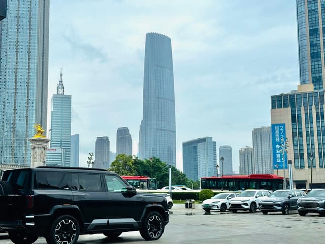 Skyline of Tianjin with modern skyscrapers and parked vehicles on a cloudy day.