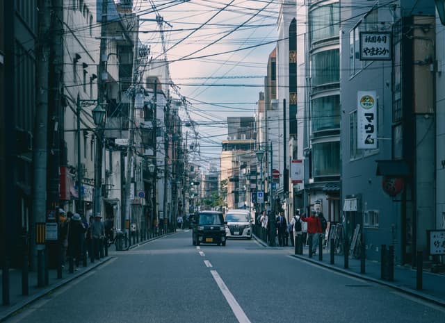 Lively urban street capturing pedestrians, vehicles, and overhead wires in a modern cityscape.