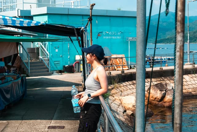 Casual scene of a woman standing at Sai Kung Pier in Hong Kong, enjoying the summer day.