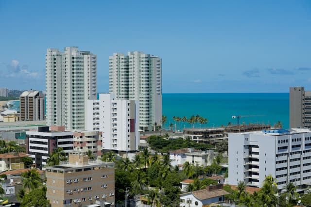High-rise buildings in Maceió offer a stunning view of the coastline under a clear blue sky.