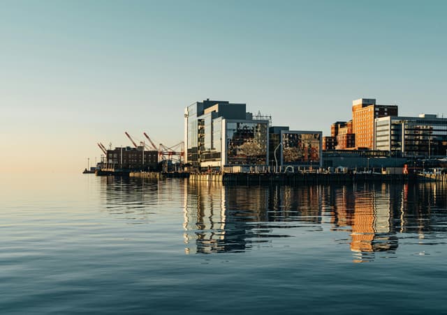 A serene view of Halifax waterfront with modern buildings reflecting on the water under a clear sky.
