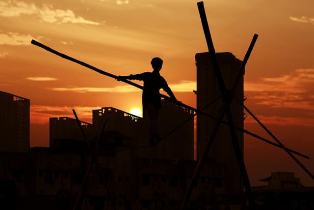 A man performing acrobatics against a dramatic sunset in Bhiwandi, India.