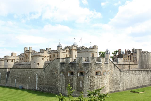 View of the historic Tower of London under a blue sky with clouds.
