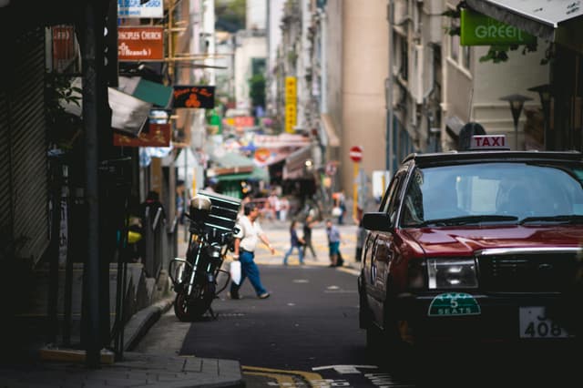 Buzzing urban life amidst shops and taxis on Hong Kong Island's lively streets, capturing its dynamic essence.