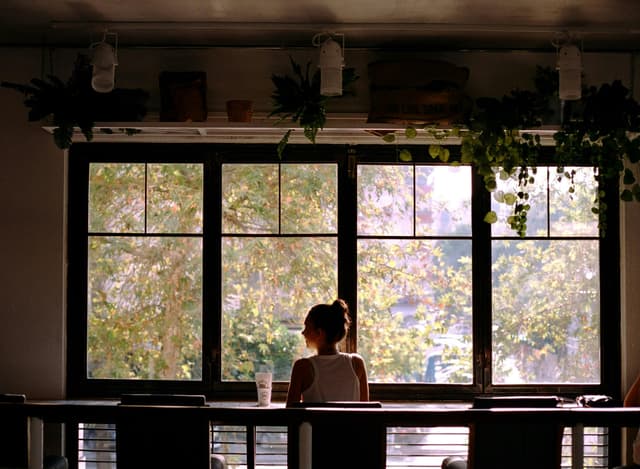 Woman sitting in a café enjoying a scenic view through the window in Adana, Turkey.