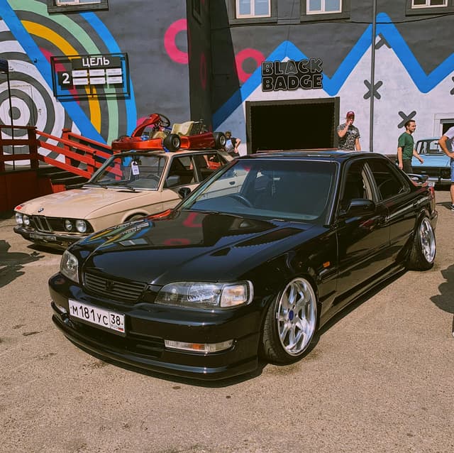 Vintage cars parked in front of vibrant mural in Irkutsk, Russia, showcasing automotive culture.
